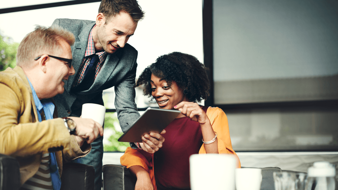 Man holding computer tablet and showing content to his coworkers. One male and one female. 