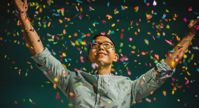 Happy person with arms outstretched as confetti drops 