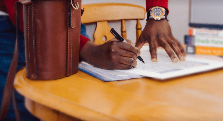 Man writing on a document at a table 