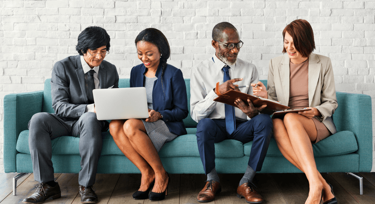 Four office employees sitting on a green sofa