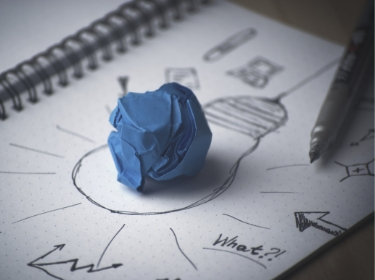 Un unmolded ball of blue clay sitting on a notepad with pen