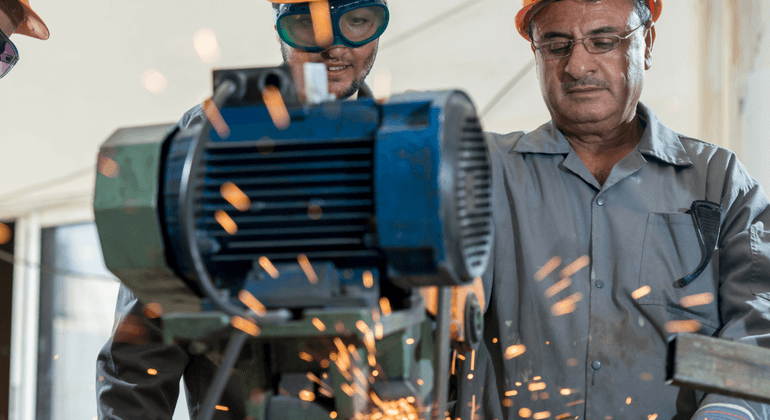 Two men working in an industrial setting with spark emitting machinery 